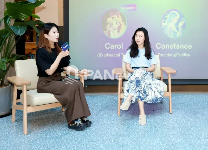 Constance Waing speaking on a panel discussion seated in an armchair.